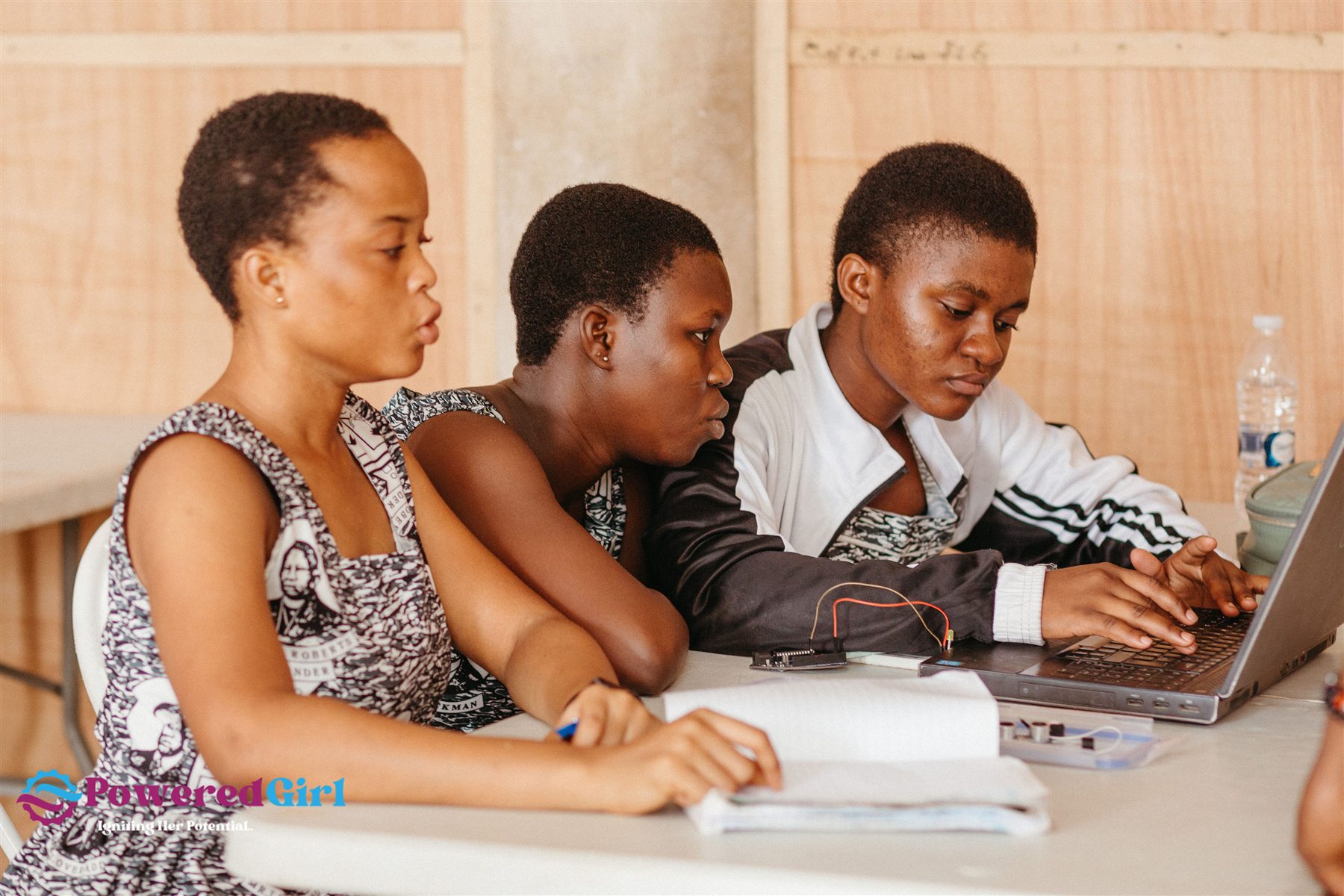 Powered Girl participants collaborating around a laptop